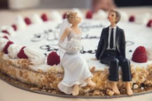 A cake featuring figurines of a husband and wife